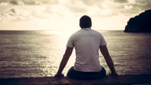 Man looking out at the ocean, symbolising reflection and the experience of being neurodivergent in a world that often seeks blame instead of belonging.